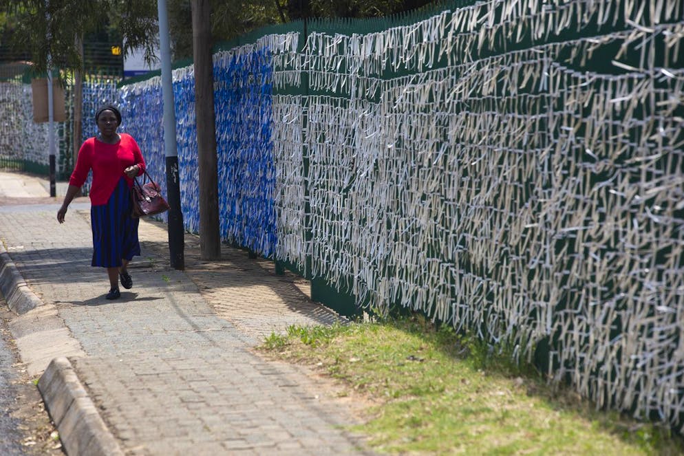 Un piéton passe devant des rubans attachés à la clôture du périmètre de l'église presbytérienne St. James à Johannesburg, le mardi 10 octobre. 19, 2021. Chaque ruban représente plus de 88 900 personnes décédées du virus dans le pays. 