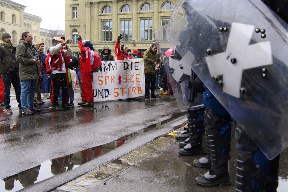 Menschen protestieren gegen Polizisten nach der Bekanntgabe der Ergebnisse waehrend die Kundgebung der Gegner des Covid-19-Gesetzes, am Sonntag, 28. November 2021, auf dem Bundesplatz in Bern. Das eidgenoessische Stimmvolk hat am Sonntag ueber drei Vorlagen zu bestimmen, die Pflegeinitiative, die Justiz-Initiative und die Aenderung vom 19. Maerz 2021 des Covid-19-Gesetzes. (KEYSTONE/Anthony Anex)