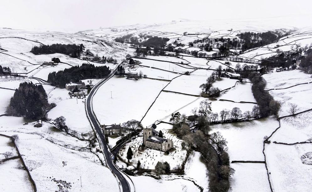 La neve copre i campi e le colline che circondano la chiesa di Santa Maria Vergine nell'Arkengarthdale, nel North Yorkshire, in mezzo a condizioni di congelamento all'indomani della tempesta Arwen.