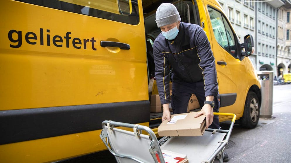 Ein Paketbote der Post stapelt waehrend der Auslieferung die Pakete auf einen Wagen, am Donnerstag, 11. Februar 2021, in Bern. (KEYSTONE/Peter Klaunzer)