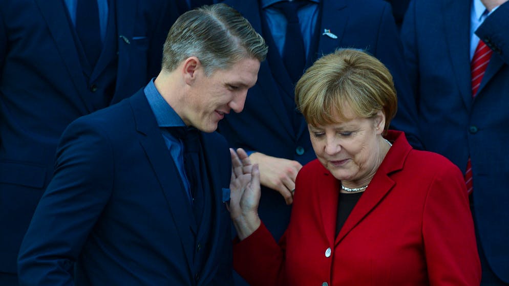 Member of the German football national team who took part in the 2014 FIFA Football World Cup striker Bastian Schweinsteiger (L) talks with German Chancellor Angela Merkel during a group photo after football players and team members received the Silver Laurel Leaf, Germany's top award for sports success, at the Schloss Bellevue Presidential Palace on November 10, 2014 in Berlin. The 23-man squad who clinched the World Cup title in Brazil, will also later receive their official World Cup winners badge from football's governing body FIFA and attend the Premiere screening of the 'Die Mannschaft' (The Team), a documentary film dedicated to them. AFP PHOTO / JOHN MACDOUGALL (Photo credit should read JOHN MACDOUGALL/AFP via Getty Images)