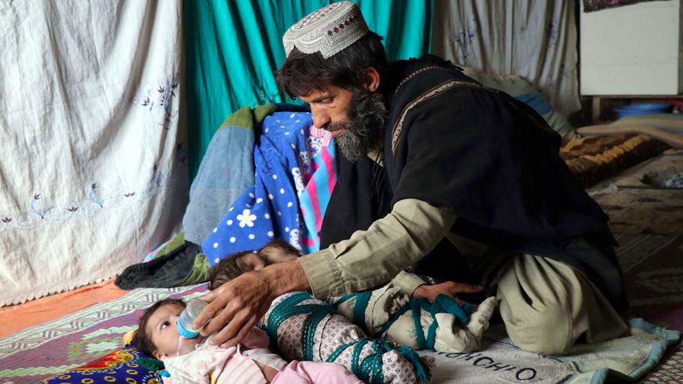 epa09625456 Ehsanullah, a father or newborn triplets sons sit next to his babies at his home in Kandahar, Afghanistan, 06 December 2021. Ehsanullahl said he was grateful to Allah for blessing him with three sons. However, he complained poverty made it difficult for him to look after them. The United Nations World Food Program (WFP) urgently called for 2.6 billion USD to address the serious humanitarian crisis in Afghanistan, where the lives of 3.2 million children face hunger and malnutrition. EPA/STRINGER