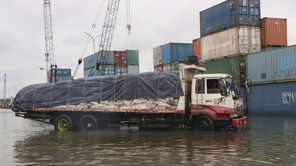 A truck drives past containers in the water during a tidal flood at the Sunda Kelapa Port in Jakarta, Indonesia, Tuesday, Dec. 7, 2021.(AP Photo/Tatan Syuflana)