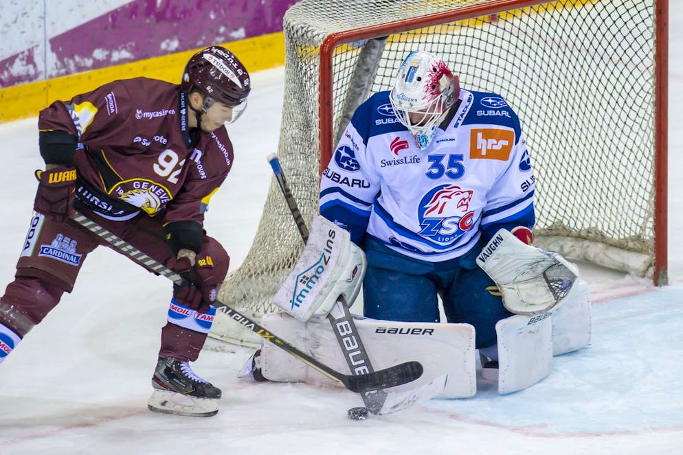 L?attaquant genevois Eliot Berthon, gauche, a la lutte pour le puck avec le gardien zuerichois Ludovic Waeber, droite, lors du match du championnat suisse de hockey sur glace de National League LNA, entre le Geneve Servette HC et le ZSC Lions, ce jeudi 9 decembre 2021 a la patinoire des Vernets a Geneve. (KEYSTONE/Martial Trezzini)
