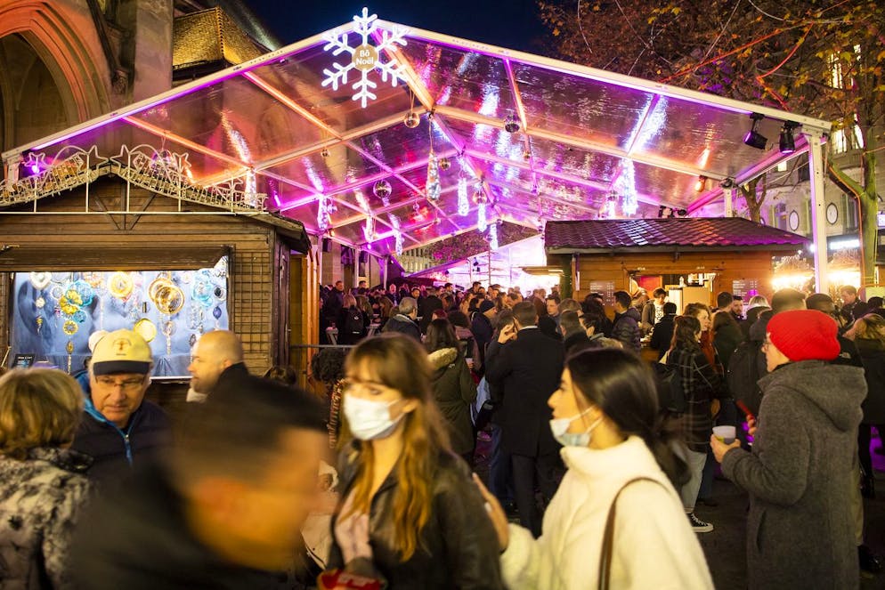 Des personnes prennent l'apéritif entre les chalets sous une tente de la place St-Francois lors de l'ouverture du "Bo Noël" le jeudi 18 novembre 2021 à Lausanne. (KEYSTONE/Jean-Christophe Bott)