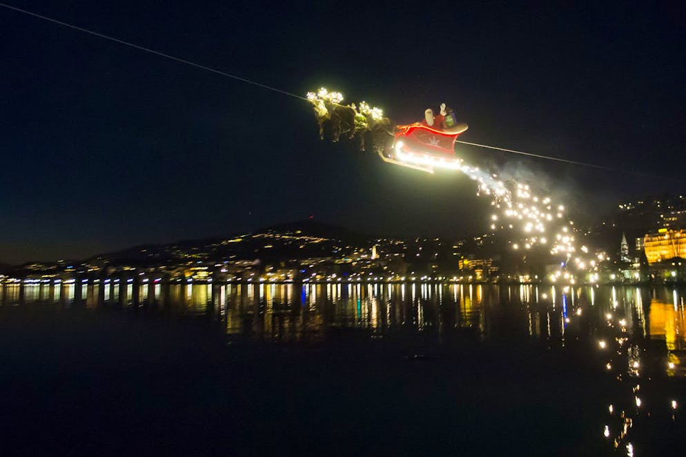 Santa Claus waves to the crowd from his flying sleigh drawn by reindeer over the Geneva Lake and in front of the Swiss and French alps at the sunset during the 20th edition of the Christmas Market in Montreux, Switzerland, Tuesday, December 23, 2014. Santa Claus is 