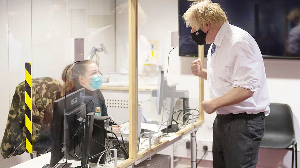 Boris Johnson, Premierminister von Großbritannien, spricht mit einer Mitarbeiterin während er ein Corona-Impfzentrum besucht. Foto: Geoff Pugh/Daily Telegraph/PA Wire/dpa