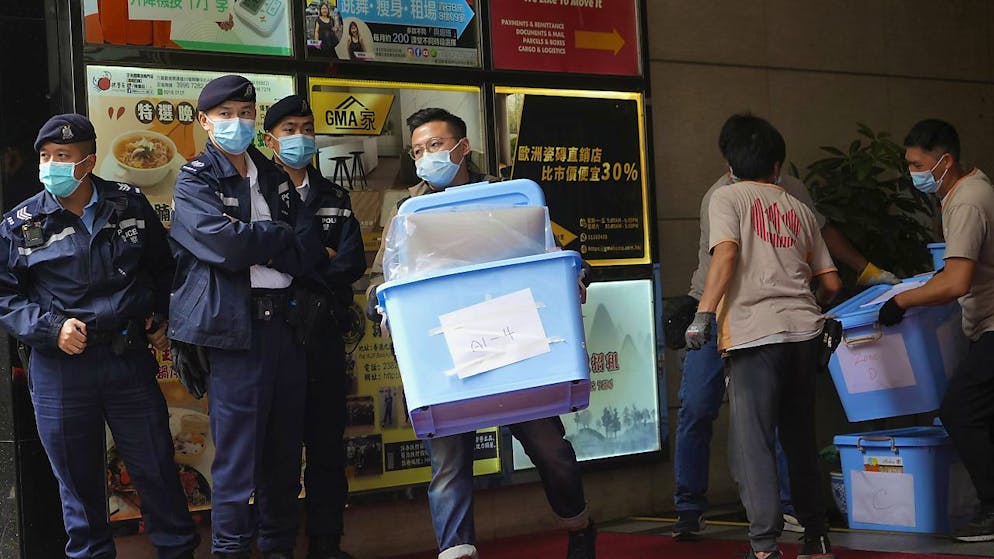 Un uomo trasporta in uno scatolone "prove" della sedizione di "Stand News", il giornale indipendente di Hong Kong finito nel mirino delle autorità.