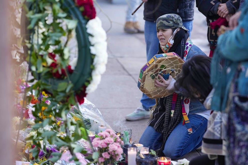 Les personnes en deuil se rassemblent devant la porte d'un salon de tatouage le long de South Broadway le mardi 28 décembre 2021, à Denver, l'une des scènes d'une fusillade qui a fait plusieurs morts, dont le tireur présumé lundi soir, et quelques autres blessés.