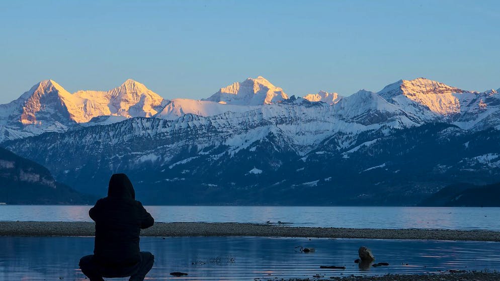Ein Mann fotografiert das Dreigestirn mit Eiger, Mönch und Jungfrau (von links) das in der Abendsonne leuchtet.