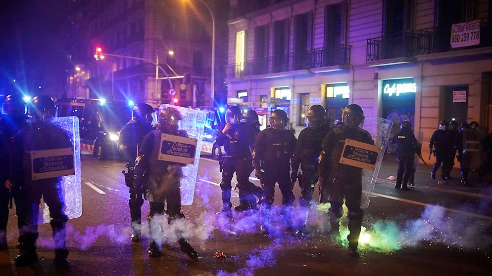 Feuerwerkskörper explodieren neben Polizisten während eines Protests gegen die Verhaftung des Rappers Pablo Hasel. Foto: Joan Mateu/AP/dpa