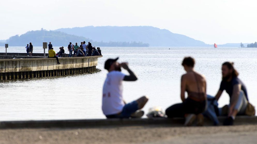 People enjoy the sun on the shore of Lake Biel during the state of emergency of the coronavirus disease (COVID-19) outbreak, in Biel, Switzerland, Monday, April 13, 2020. Countries around the world are taking increased measures to stem the widespread of the SARS-CoV-2 coronavirus, which causes the Covid-19 disease. (KEYSTONE/Anthony Anex)