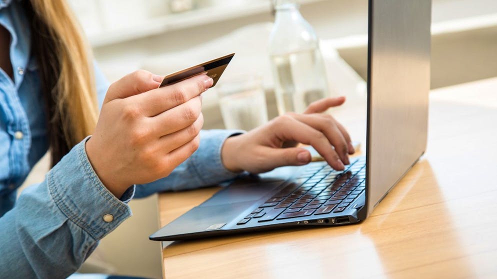 ARCHIV - 01.10.2020, Brandenburg, Wittenberge: Eine Frau tippt die Nummer ihrer Kreditkarte in ein Laptop. Viele Verbraucher zahlen ihre Einkäufe im Internet per Kreditkarte. Ab 2021 gelten dafür strengere Sicherheitsanforderungen - spätestens vom 15. März an. (zu dpa