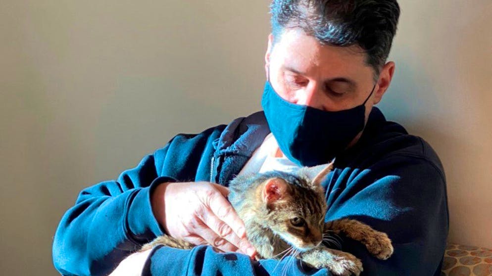This photo provided by the Los Angeles County Department of Animal Care and Control shows Brandy, a brown tabby cat, that was reunited on Monday, Feb. 22, 2021, with her owner, Charles, (he would only give his first name) after she went astray for 15 years, are seen together at the Palmdale, Calif., animal care center. The Los Angeles man adopted her as a 2-month-old kitten in 2005. Charles says he cried and Brandy purred in his arms. The brown tabby was found Sunday in Palmdale, about a half-hour's drive from where he lives. (Los Angeles County Department of Animal Care and Control via AP)