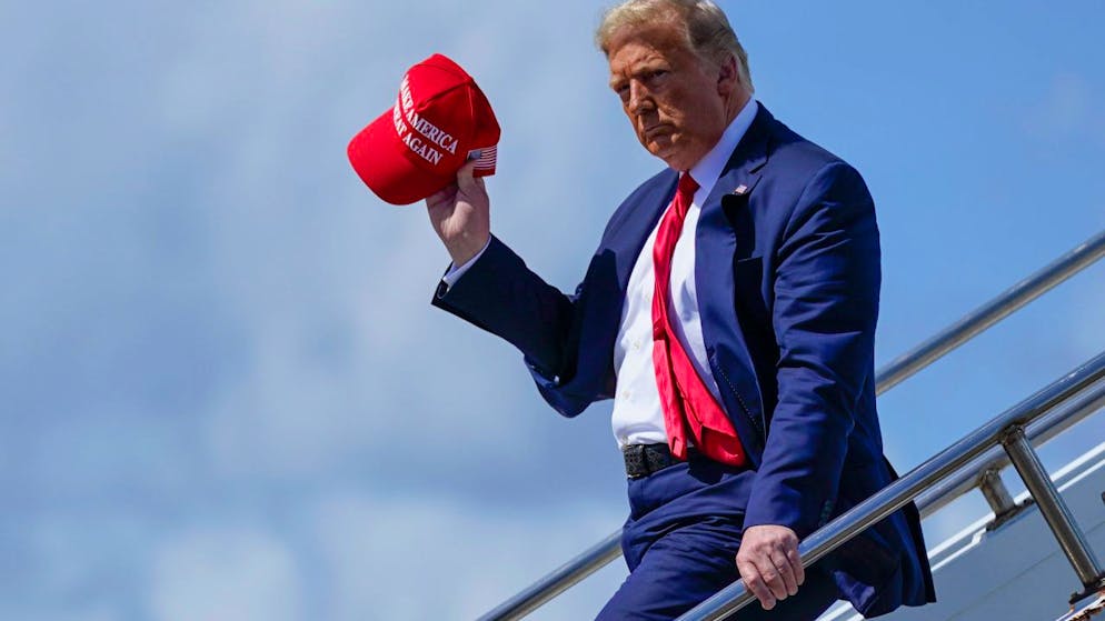 ARCHIV - Donald Trump, damaliger Präsident der USA, steigt am Internationalen Flughafen aus dem Flugzeug und winkt mit der «Make America Great Again»-Kappe. Foto: Evan Vucci/AP/dpa