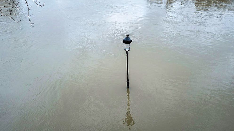 Eine Strassenlaterne ragt aus dem Wasser der Seine in Paris heraus.
