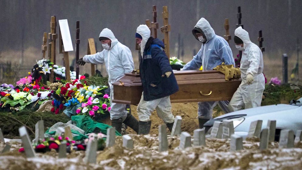 FILE In this file photo taken on Tuesday, Dec. 15, 2020, Grave diggers wearing protective suits carry the coffin of a COVID-19 victim in the section of a cemetery reserved for coronavirus victims in Kolpino, outside St.Petersburg, Russia. Russia's updated statistics on coronavirus-linked deaths showed that over 100,000 people with COVID-19 had died in the pandemic by December, a number much higher than previously reported by government officials. According to the data released Monday by Russia's state statistics agency, Rosstat, a total of 116,030 people with COVID-19 died in Russia between April and November. The count included cases where the virus was not the main cause of death and where the virus was suspected but not confirmed. (AP Photo/Dmitri Lovetsky, File)
