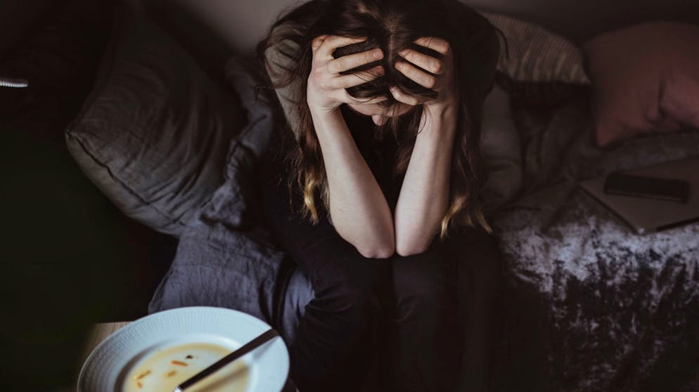 Junge Frau deprimiert, traurig, verzweifelt, mit leerem Teller, Essstörung