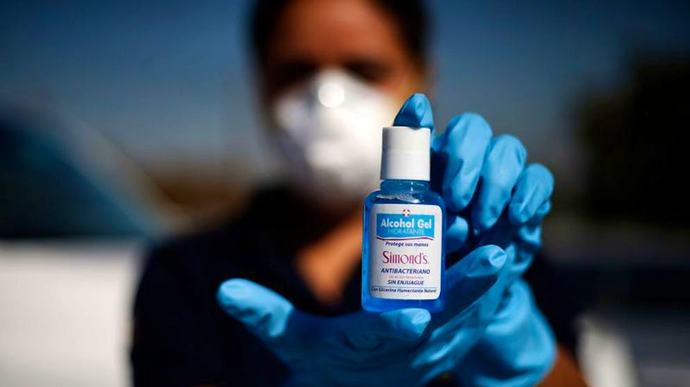 ARCHIV - 18.03.2020, Chile, Santiago: Ein Polizistin zeigt eine kleine Flasche mit Alkohol-Gel, die als Teil einer größeren Ladung nicht genehmigten Materials von Polizei beschlagnahmt wurde. Das Produkt wurde ohne Genehmigung produziert und verkauft. (zu dpa «Corona-Kriminalität: Wie Gauner an der Pandemie verdienen» vom 09.02.2021) Foto: Cristobal Escobar/Agencia Uno/dpa +++ dpa-Bildfunk +++
