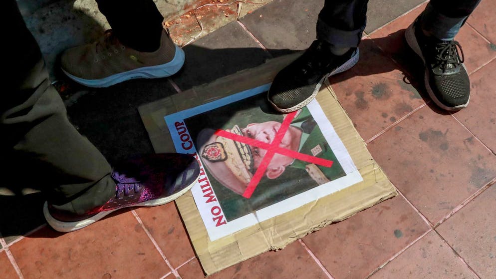 Demonstranten treten auf ein durchgestrichenes Bild des Oberbefehlshabers des Militärs von Myanmar.