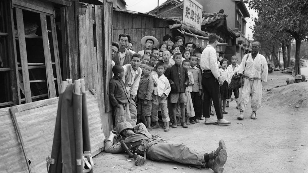 Fatigue, not an enemy bullet, stopped this American marine who catches 40 winks on a Seoul Street unperturbed by his audience of young and old residents in Seoul, Sept. 28, 1950. (AP Photo/Max Desfor)