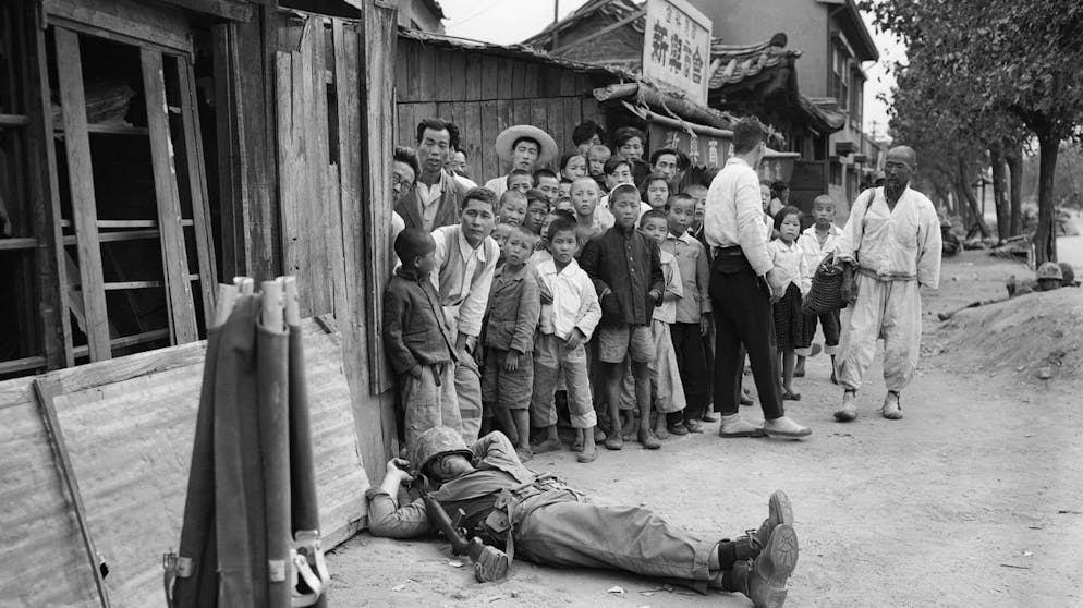Fatigue, not an enemy bullet, stopped this American marine who catches 40 winks on a Seoul Street unperturbed by his audience of young and old residents in Seoul, Sept. 28, 1950. (AP Photo/Max Desfor)