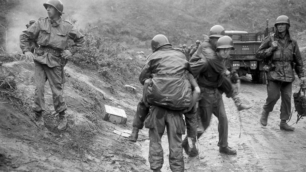 FILE - In this Oct. 5, 1951 file photo, American soldiers are carried on the backs of other GI's from Heartbreak Ridge through the rain to an aid station just behind the front lines in South Korea during the Korean War. The 2nd Division GI's, wounded in an ambush as they came off the Ridge for a two-day rest, had spent two weeks in the line during the height of the bloody battle on the east central front. (AP Photo)