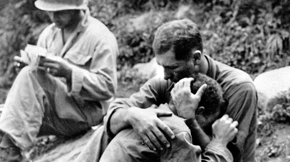 ** FILE ** An American infantryman, his buddy killed in action in the Korean War, weeps on the shoulder of another GI somewhere in Korea, in this Aug. 28, 1950 file photo. Meanwhile, a corpsman, left, goes about the business of filling out casualty tags. Al Chang was a dock worker at the 1941 attack on Pearl Harbor who became a celebrated combat photographer, both as a journalist and a soldier. Chang, who was twice nominated for a Pulitzer Prize, died late Sunday in Honolulu, his family said. He had celebrated his 85th birthday on July 13, with family and friends gathering to share memories of his life and acclaimed photography of three wars. (AP Photo/Al Chang, file)