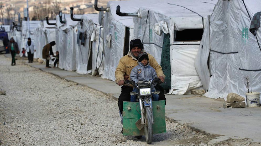 A Syrian displaced man and his son ride a motorcycle, as they drive between the tents at a refugee camp, in Bar Elias, in eastern Lebanon's Bekaa valley, Friday, March 5, 2021. Syria has been mired in civil war since 2011, after Syrians rose up against President Bashar Assad amid a wave of Arab Spring uprisings. Nearly ten years later, millions of displaced Syrians unlikely to return in the foreseeable future, even as they face deteriorating living conditions abroad. The Syrian conflict has resulted in the largest displacement crisis since World War II. (AP Photo/Hussein Malla)