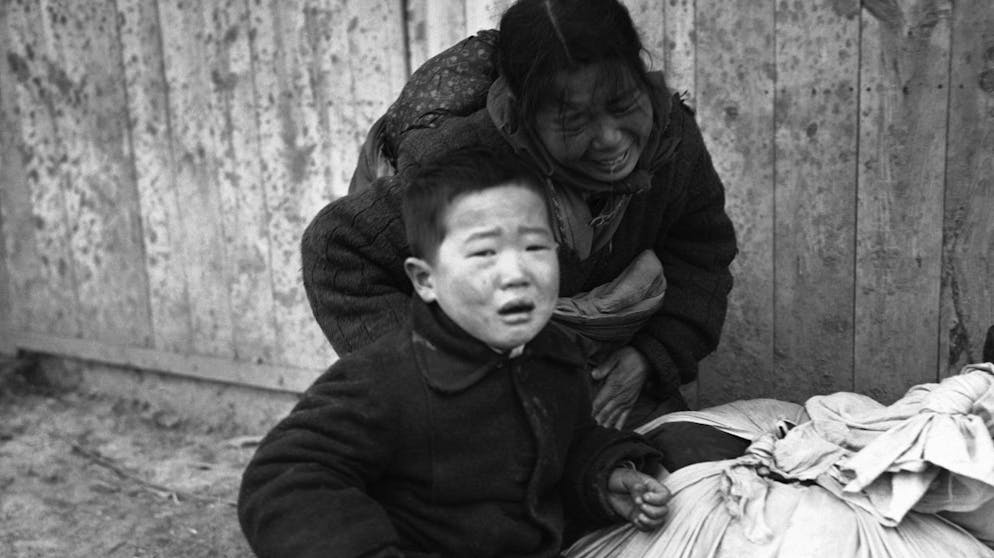 A Korean mother, bent over by pain, sobs as she halts with her child, unable to continue her flight from the fighting zone in the Osan area south of Seoul, South Korea, Jan. 14, 1951. (AP Photo/Max Desfor)