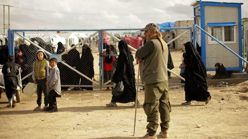 FILE - In this March 31, 2019 file, photo, boys watch a Kurdish guard at Al-Hol camp, at the gate to the section where foreign families from Islamic State-held areas are housed, Hassakeh province, Syria. Killings have surged inside the camp with at least 20 men and women killed in January, 2021. They are believed to be the victims of IS militants trying to enforce their power inside the camp housing 62,000 people, mostly women and children. (AP Photo/Maya Alleruzzo, File)