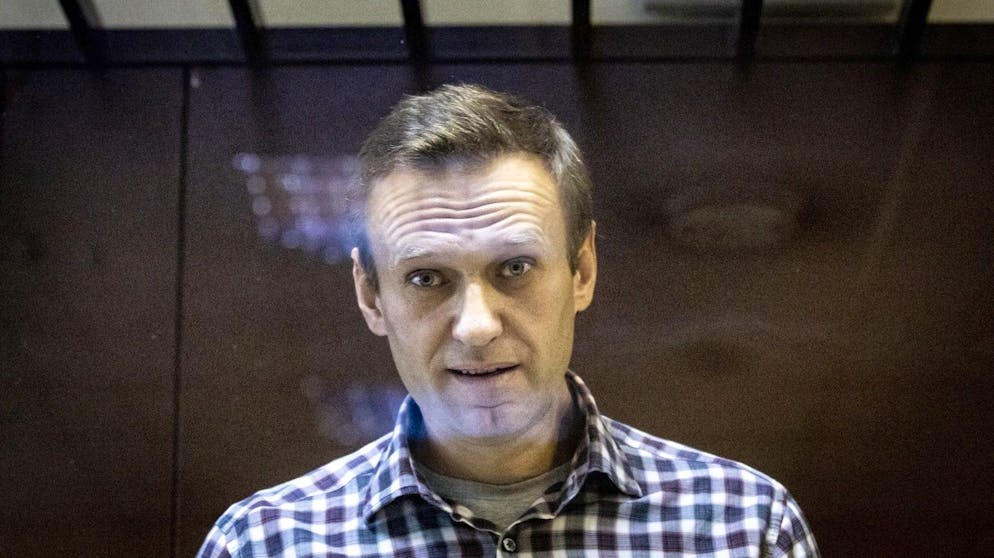 Russian opposition leader Alexei Navalny looks at photographers standing behind a grass of the cage in the Babuskinsky District Court in Moscow, Russia, Saturday, Feb. 20, 2021. A Moscow court has rejected Russian opposition leader Alexei Navalny's appeal against his prison sentence. Earlier this month, a lower court sentenced Navalny to two years and eight months in prison for violating terms of his probation while recuperating in Germany from a nerve agent poisoning that he blames on the Kremlin. (AP Photo/Alexander Zemlianichenko)