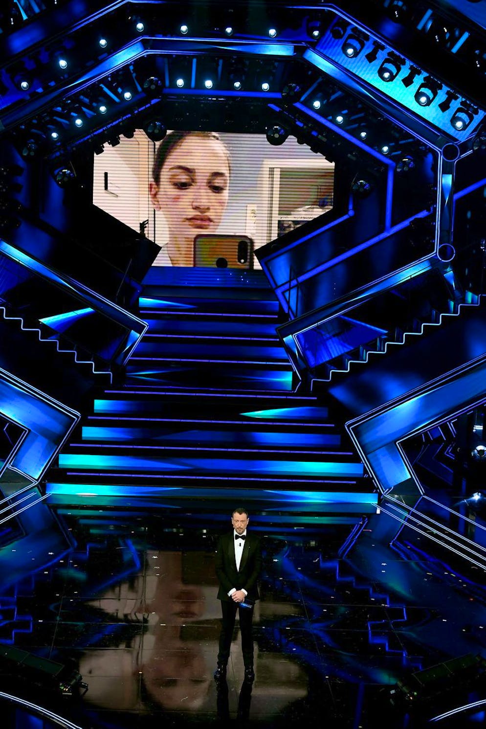epa09047498 Sanremo Festival host and artistic director, Amadeus introduces Alessia Bonari, on the stage of the Ariston theatre during the 71st Sanremo Italian Song Festival, Sanremo, Italy, 02 March 2021. The festival runs from 02 to 06 March 2021. Bonari is a nurse of a hospital in Milan who became a symbol of the fight against COVID-19 when a photo of her (seen in background), taken at the beginning of March with the lockdown just started, showed her swollen face from wearing a protective mask during a very long shift, went viral on the Internet. EPA/ETTORE FERRARI