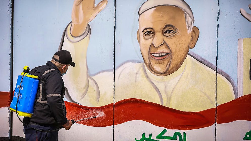 Ein Arbeiter versprüht Desinfektionsmittel an einem Wandgemälde von Papst Franziskus in Bagdad. Foto: Ameer Al Mohammedaw/dpa