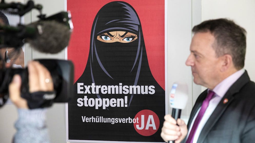 Walter Wobmann, Initiator der Initiative «Ja zum Verhüllungsverbot», gibt neben einem Plakat mit der Aufschrift «Extremismus stoppen» ein Interview.