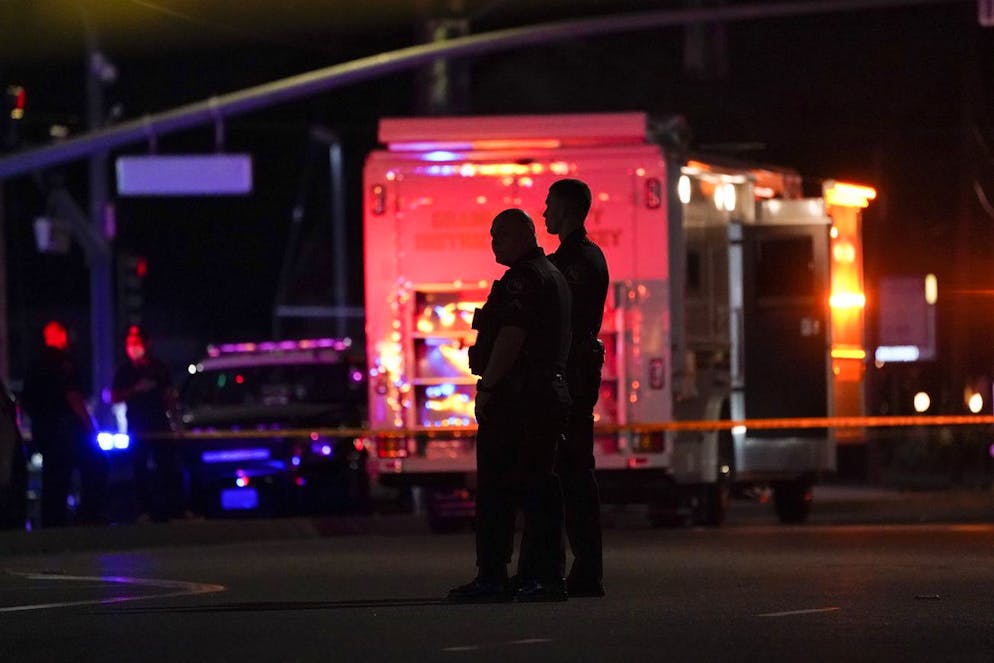 Two police officers stand outside an office building where a shooting occurred in Orange, Calif., Wednesday, March 31, 2021. The shooting killed several people, including a child, and injured another person before police shot the suspect, police said. (AP Photo/Jae C. Hong)