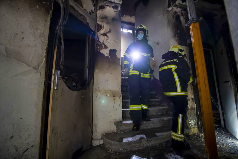 Des sapeurs pompier volontaire, s'affairent sur l'incendie d'un immeuble a la rue Royaume, ce dimanche 10 janvier 2021 a Geneve. Les pompiers sont intervenus en force, pour eteindre un incendie qui s'etait declare dans l'allee d'un immeuble, dans le quartier des Paquis. 46 personnes ont ete evacuees et 20 ont ete relogees provisoirement dans un abri de la Protection civile. (KEYSTONE/Martial Trezzini)