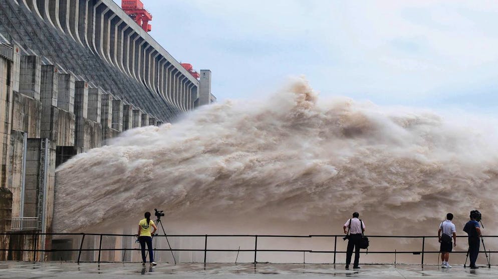 In this photo released by China's Xinhua news agency, journalists take photos as flood water is released from the Three Gorges Dam's floodgates in Yichang, in central China's Hubei province, Tuesday, July 20, 2010. Rescuers were searching Tuesday for 30 people buried in landslides as flood waters from days of heavy rain surged past the Three Gorges Dam, the world's largest. (AP Photo/Xinhua, Cheng Min) ** NO SALES **