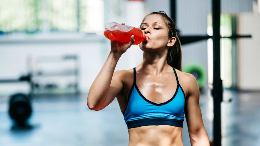 Sportgetränk, junge Frau trinkt Sportgetränk in Fitnessstudio