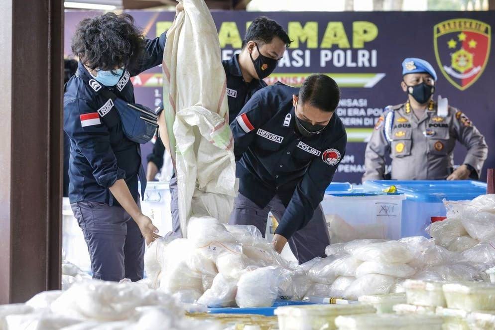 Coraggio da vendere!. Bel colpo! Poliziotti indonesiani dispongono per terra il prodotto di un grosso sequestro in occasione di in una conferenza stampa presso la sede della polizia nazionale a Giacarta. La polizia indonesiana ha confiscato 2,5 tonnellate di metanfetamina in cristalli provenienti da una rete internazionale di narcotraffico operante in Medio Oriente, Malaysia e Indonesia. (28 aprile 2021)