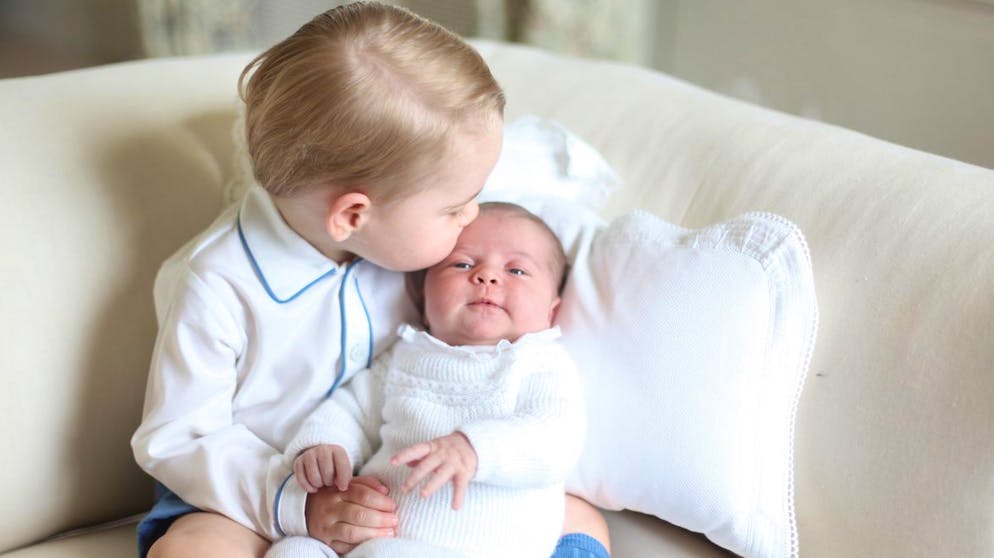 This image made available by Kensington Palace Saturday, June 6, 2015, taken by Kate, Duchess of Cambridge, at Anmer Hall, eastern England in mid-May 2015 shows Britain's Princess Charlotte, right, being held by her brother, 2-year-old, Prince George. Britain's royals have been photographed by some of the world's leading photographers. But Prince William and Kate are continuing a more informal tradition begun two years ago with the first official portrait of Prince George, taken by his grandfather Michael Middleton. Charlotte was born May 2 and is fourth in line to the throne. (Duchess of Cambridge via AP) MANDATORY CREDIT