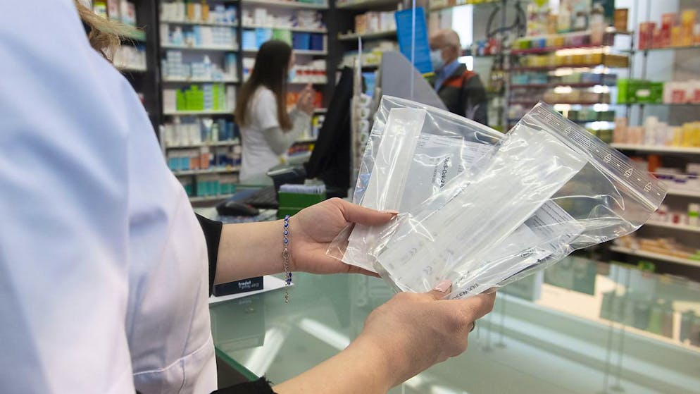 Eine Apothekerin zeigt abgepackte Coronavirus Antigen-Selbsttests.