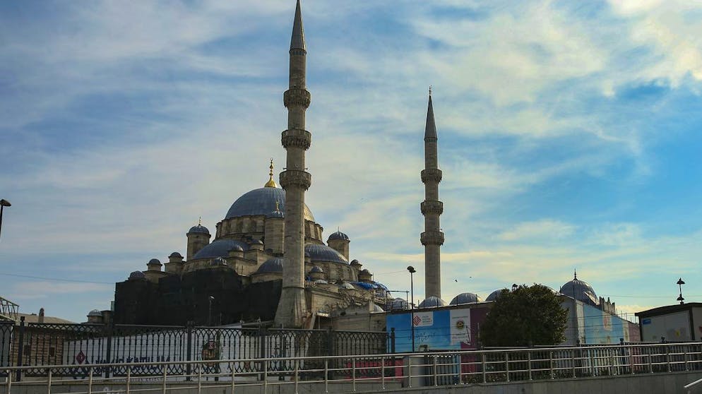 A child plays music for money backdropped by the Yeni Cami (New Mosque) in Istanbul, Saturday, April 3, 2021. The streets of Istanbul, reflect a weekend curfew resumed as the number of COVID-19 cases hit record levels, and with renewed restrictions announced for the Islamic month of Ramadan which begins on April 13. (AP Photo/Emrah Gurel)