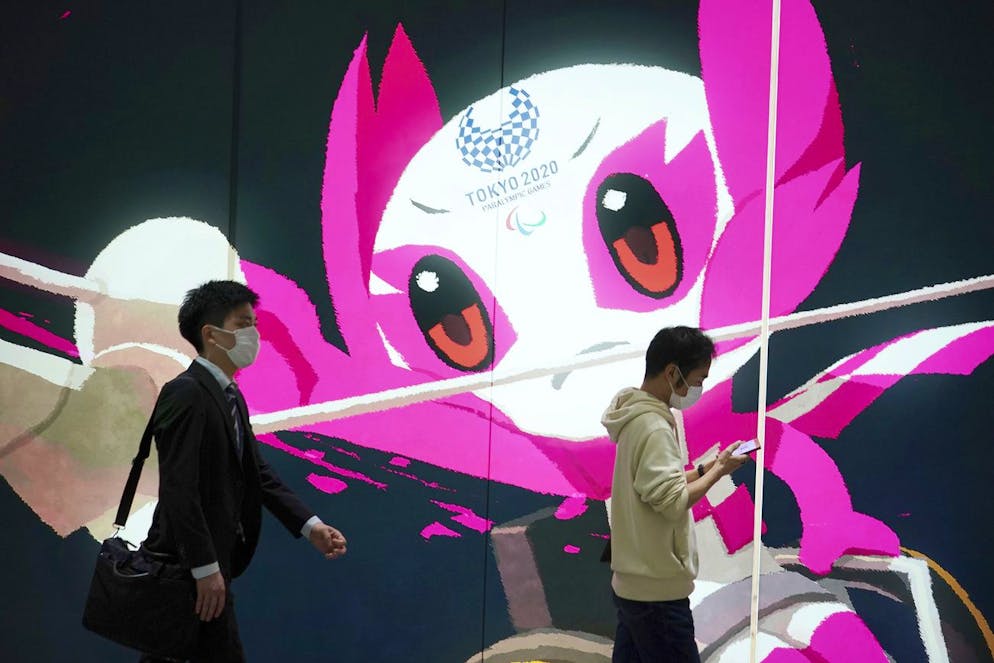 People wearing protective masks to help curb the spread of the coronavirus walk near an advertisement of the Tokyo 2020 Paralympic Games Friday, May 14, 2021, in Tokyo. The Japanese capital confirmed more than 850 new coronavirus cases on Friday. (AP Photo/Eugene Hoshiko)