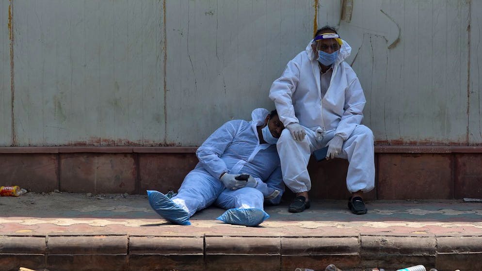 Pflegekräfte gönnen sich vor einem Spital in der indischen Hauptstadt Neu-Delhi eine Verschnaufpause.