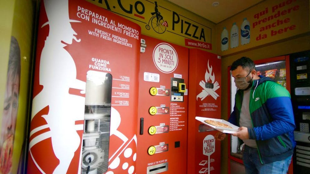 A man collects his order at an automatic pizza vending machine, the first of its kind in downtown Rome on April 29, 2021, its capable of kneading, seasoning, cooking and delivering the pizza in a carton box in three minutes only. (Photo by Filippo MONTEFORTE / AFP) (Photo by FILIPPO MONTEFORTE/AFP via Getty Images)