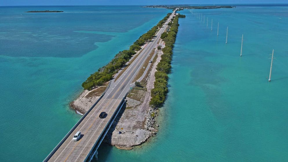 In this aerial photo provided by the Florida Keys News Bureau, vehicular traffic on the Florida Keys Overseas Highway is extremely light Tuesday, March 24, 2020, in Islamorada, Fla. The subtropical island destination is temporarily closed to visitors until further notice due to the coronavirus crisis, according to local officials. Tourism is the Keys' top industry, employs about half of the region's workforce and generates almost $2 billion annually for the area's economy. (Andy Newman/Florida Keys News Bureau via AP)