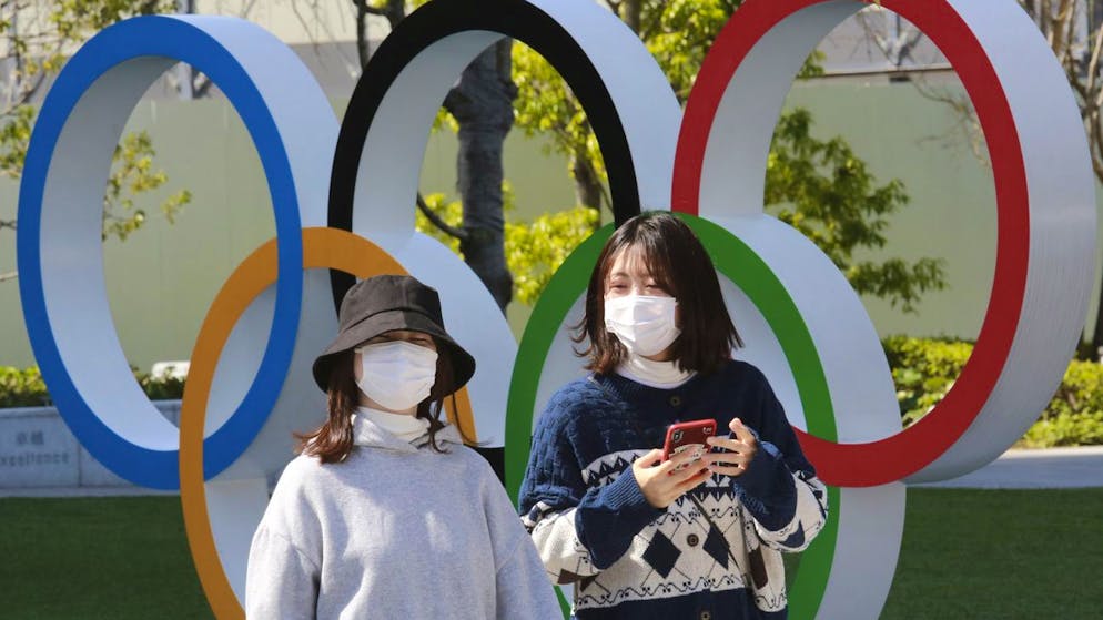 FILE - In this March 17, 2021, file photo, people walk past the Olympic rings in Tokyo. The Tokyo Olympics open in under four months, and the torch relay has begun to crisscross Japan with 10,000 runners. Organizers say they are mitigating the risks, but many medial expert aren't convinced.(AP Photo/Koji Sasahara)