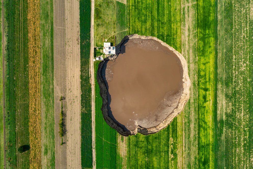 SANTA MARIA ZACATEPEC, MEXICO - JUNE 09: Aerial view of a giant sinkhole on June 09, 2021 in Santa María Zacatepec, Mexico. The giant sinkhole is located 20 kilometers northwest from the capital city Puebla, the hole now measures 110 meters across its widest point, covering around 11,000 square meters and damaging a house built near the place where it appeared. Farmers of the surroundings have been affected since they are not allowed to enter their fields due to the warning perimeter set up by the authorities. (Photo by Hector Vivas/Getty Images)