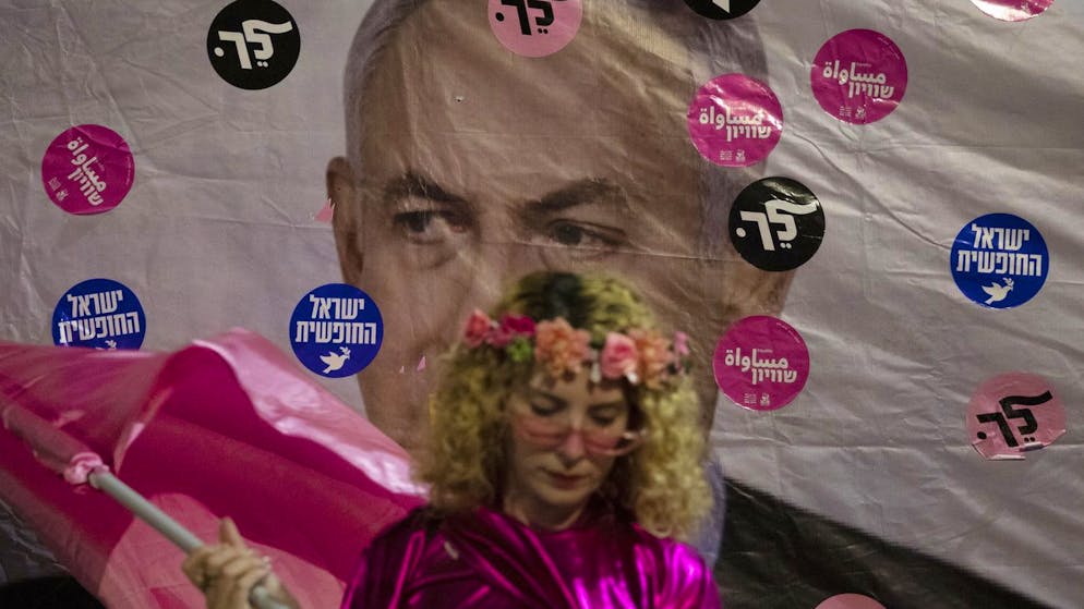 An Israeli protester wears pink during a demonstration against Israeli Prime Minister Benjamin Netanyahu outside his official residence in Jerusalem, Saturday, June 12, 2021. If all goes according to plan, Israel will swear in a new government on Sunday, ending Prime Minister Benjamin Netanyahu's record 12-year rule and a political crisis that inflicted four elections on the country in less than two years. Hebrew reads: